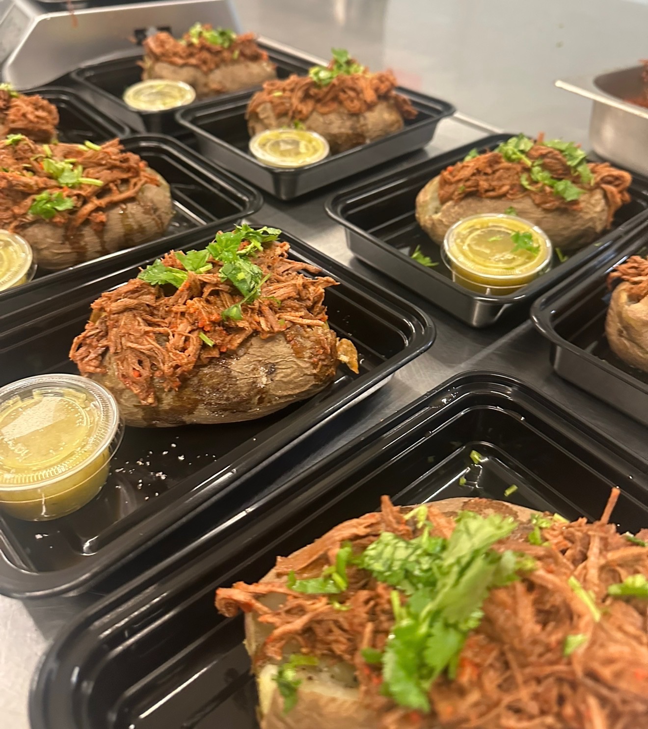 Loaded baked potatoes topped with shredded beef birria and cilantro